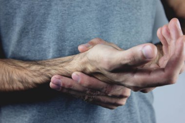 Bir adam ağrıyan elini tutuyor.