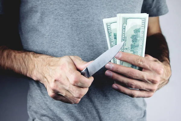 Ένας εγκληματίας με ένα μαχαίρι στο χέρι και τα λεφτά του. — Φωτογραφία Αρχείου