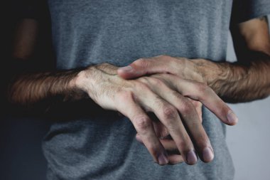 Bir adam ağrıyan elini tutuyor.