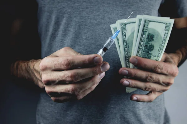 Homme tenant une seringue et de l'argent — Photo