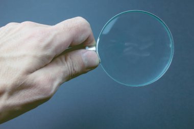 Adam elinde büyüteç tutuyor.