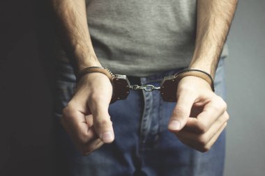 karanlık arka planda genç adam el kelepçeleri