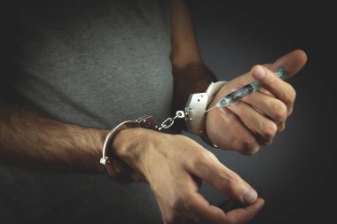 elleri kelepçeli bir şırınga tutuyor
