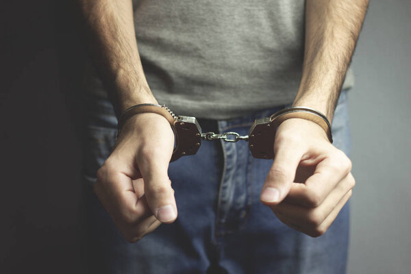 young man hand handcuffs on dark background