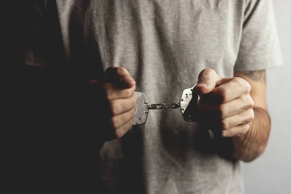 Young man hand handcuffs on dark background — Stock Photo, Image