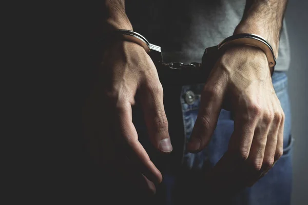 Junger Mann legt Handschellen auf dunklem Hintergrund an — Stockfoto