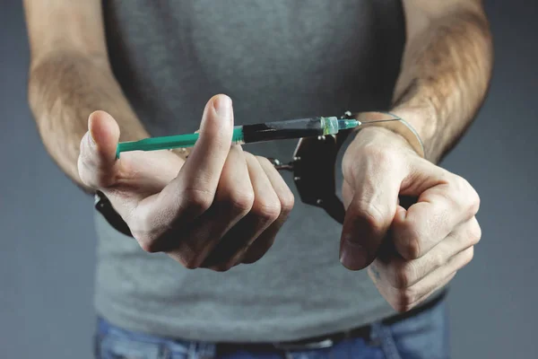 Hands holding a syringe in handcuffs — Stock Photo, Image