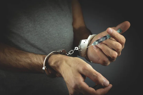 Hands holding a syringe in handcuffs — Stock Photo, Image