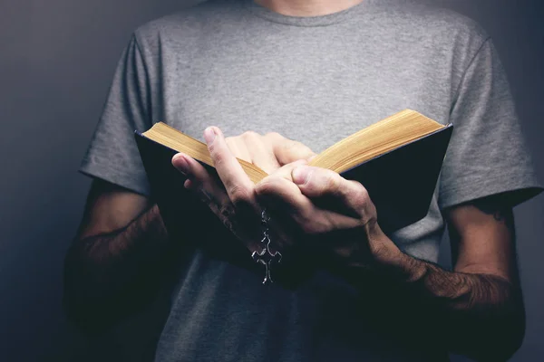 Hombre sosteniendo una cruz y una biblia en sus manos — Foto de Stock