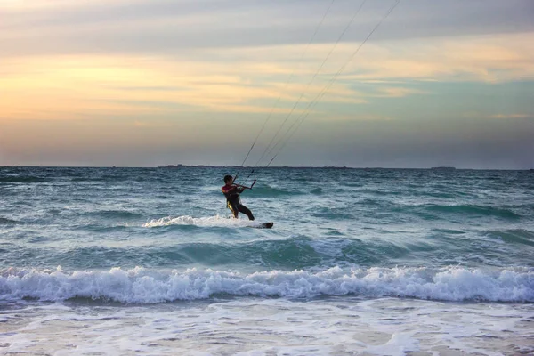 Genç sörfçü gün batımında dalgalara biner.