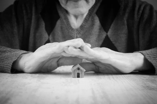 wrinkled hands protecting small house