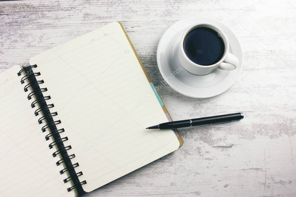 coffee with a notebook and pens on the table