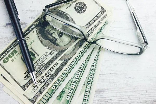 Dinero con gafas y bolígrafo sobre la mesa — Foto de Stock