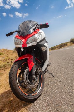 Yolda siyah ve kırmızı bir motosiklet var..