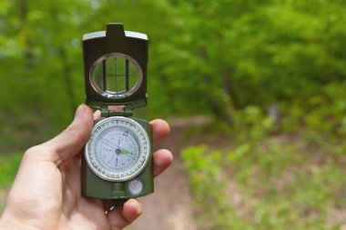 Yeşil ormanın arka planında bir turistin elinde pusula