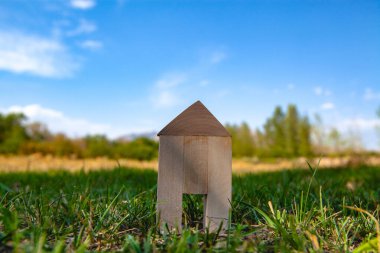 Mavi gökyüzü ve bulutlu yeşil çimenler üzerinde ahşap ev modeli