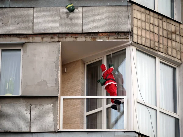 Noel Baba bir sırt çantası ile çok öykülü bir bina balkonda ipten aşağı gel. Üst katta asılı paket kahve var. Zaten tatil hediye senin ev halkı için sipariş?
