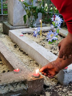 Köstebek Hıristiyan geleneğinde onurlandıran işlemi. Kadın mezar üzerinde kalp şeklinde lamba ışık için eğildi. Hıristiyanlık altın sembolü onun boynundan asmak.