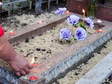 Hıristiyan geleneğinde ölenleri onurlandırma süreci. Kadın, kalp şeklindeki lambaları ve mumları yakmak için mezarın üzerine eğildi. Kırmızı olanlar aşkı sembolize eder, ve beyaz olanlar - dinlendirici ruhlar.