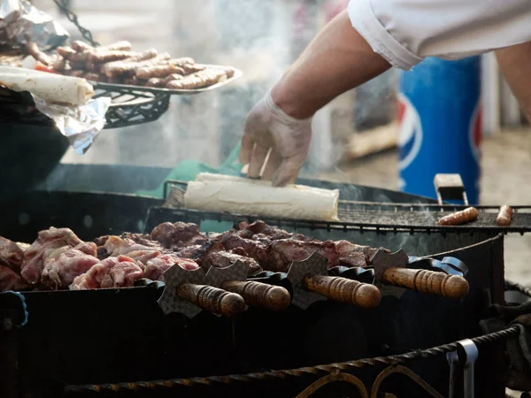 Sokak aşçısının işyeri. Kızartma kebabı. Arka planda, bir şef sosisli sandviç yuvarlıyor.. 