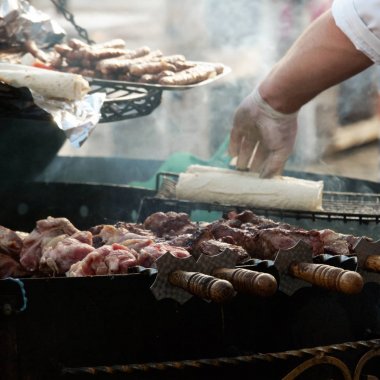 Sokak aşçısının işyeri. Kızartma kebabı. Arka planda, bir şef sosisli sandviç yuvarlıyor.. 