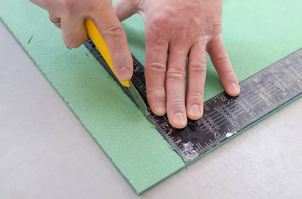 Man cuts the sound insulation Board with a knife. Eco plates from the noise.