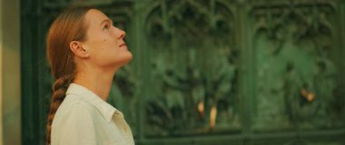 Dini oymalarla katedralin mimari kapısına bakan bir kadın..