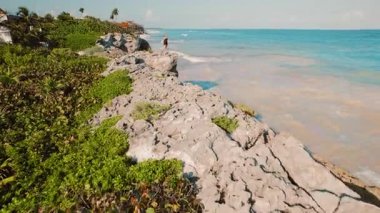 Yucatan 'daki turkuaz denize bakan kayalık kayalıklarda duran düşünceli kadın..