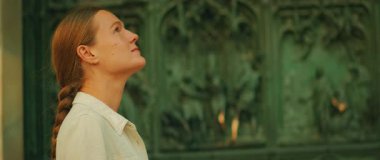 Dini oymalarla katedralin mimari kapısına bakan bir kadın..