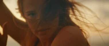 Gün batımı kıyı şeridinde enerjik bir şekilde dans ederken yüzü kıllı kadının yakın görüntüsü.