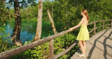 Kadınlar, yazın Plitvice 'deki tahta yolda sakin gölün kenarında huzurlu bir anın tadını çıkarırlar..