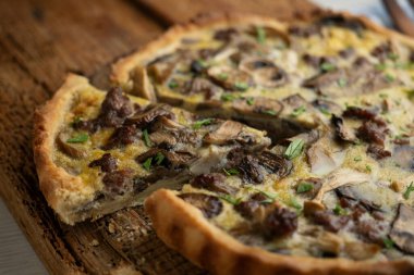 Tahta bir masada yabani mantarlı kiş, yumurta ve sığır eti..