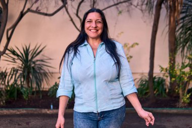 Güzel, gülümseyen, karizmatik ve neşeli bir Latin yöneticinin portresi, doğal bir parkta tutum ve feminizmle poz veriyor. İyilik, yaşlılık, güzellik..                               