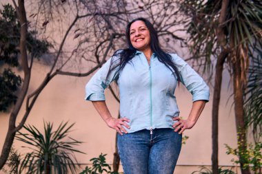 Güzel, gülümseyen, karizmatik ve neşeli bir Latin yöneticinin portresi, doğal bir parkta tutum ve feminizmle poz veriyor. İyilik, yaşlılık, güzellik..                               