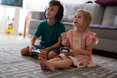 Yakın çekim kardeşler evde halı üzerinde video oyun oynarken denetleyicileriyle