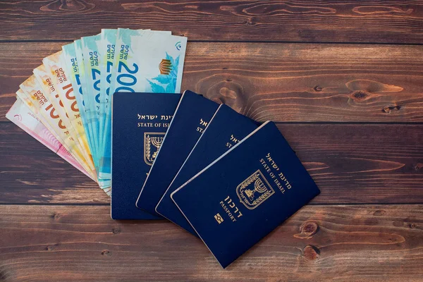 Passport with a note shekel on a wooden table.