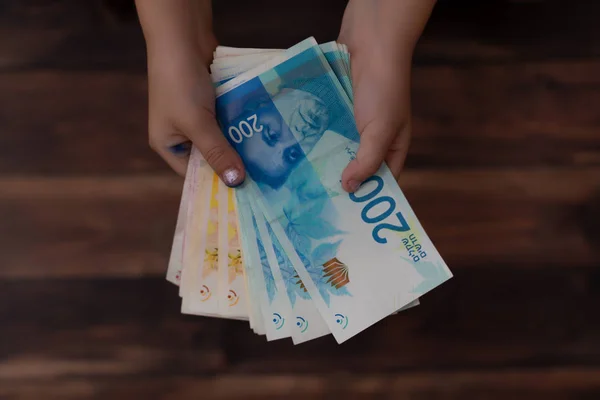 Concept of paying money, two hands of children holding Israeli banknotes in 200 shekels ILS — Stock Photo, Image