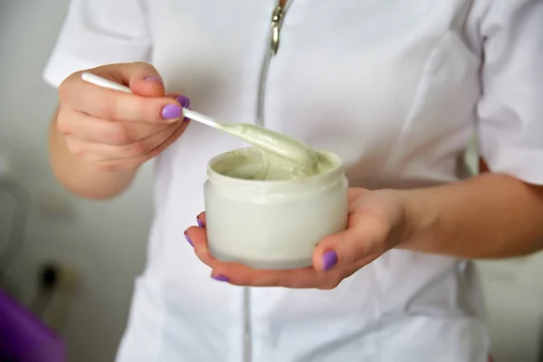 Cosmetologist hands, preparing cleansing mask. Close-up shot of jar with facial beauty cream