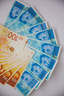 Beyaz arka plan üzerinde bir kağıt klibi yığınındaki yeni İsrail sheqalim