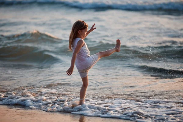 Kislány fut át a víz egy csobbanás. az ő kezében ruhával — Stock Fotó
