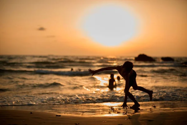 Pequeña silueta de gimnasta en la playa al atardecer —  Fotos de Stock