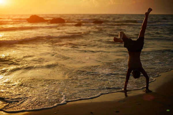 Pequeña silueta de gimnasta en la playa al atardecer —  Fotos de Stock