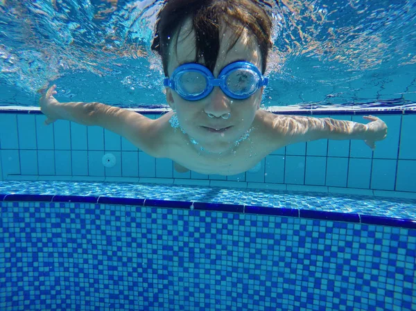 Glücklicher kleiner Junge schwimmt und taucht unter Wasser, kleiner Brustschlag mit Spaß im Pool. — Stockfoto