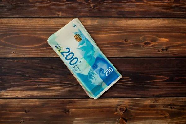 Ahşap arka plan üzerinde 200 İsrail Yeni Şekeli değer birkaç yeni banknotlar