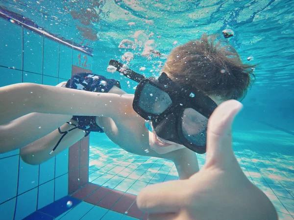 Счастливый мальчик плавает и ныряет под воду, детский инсульт груди с весельем в бассейне . — стоковое фото