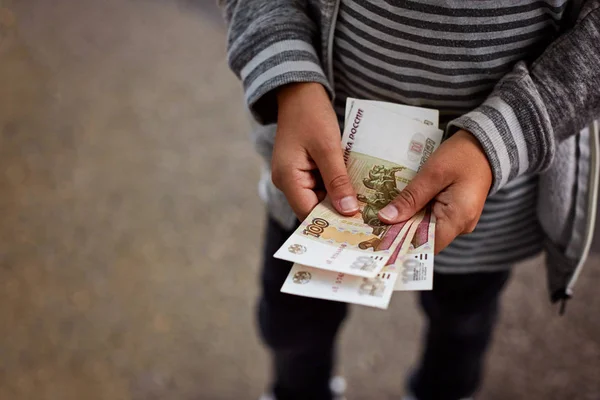 Çocuk Rus para, 100 ruble ile ilgili notlar düşünüyor.