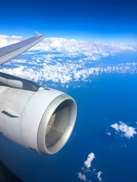 Vista del pasajero a través de la ventana de un avión a reacción que muestra el cielo, nubes, motor a reacción y ala . — Foto de Stock