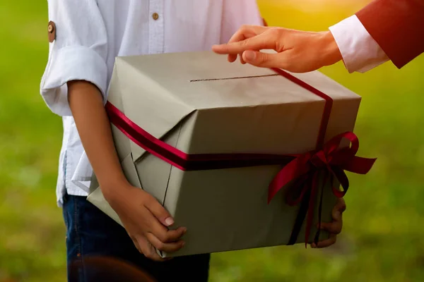 Primer plano joven asiático hombre sosteniendo un navidad rojo regalo caja en sofá y navidad árbol fondo en casa — Foto de Stock