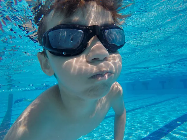 Маленький мальчик плавает под водой в бассейне — стоковое фото