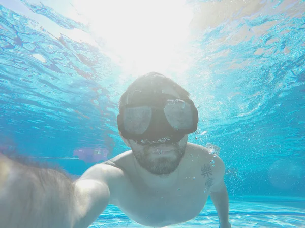Sonriente hombre nada bajo el agua cristalina —  Fotos de Stock